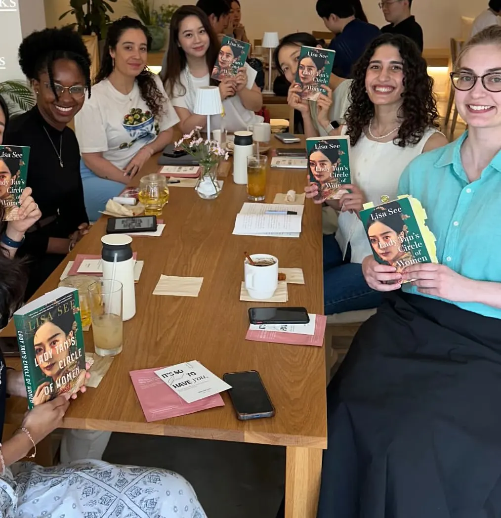 A long cafe table full of readers at a book club meet-up in Seoul